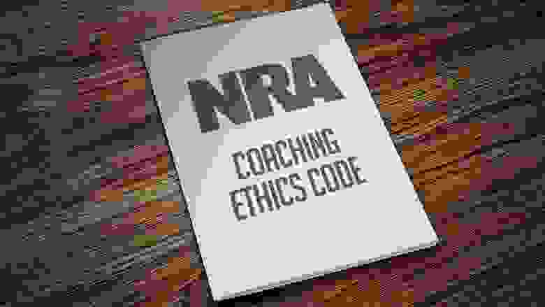 NRA Coaching Ethics Code Manual Laying on a Wooden Desk