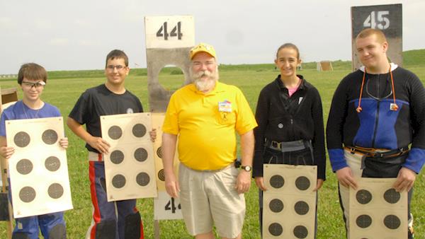 Lineup of Young Competitors Holding up Their Targets with Their Coach